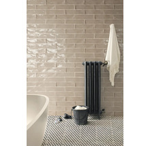Badkamer met wandtegels, radiator en bad.
