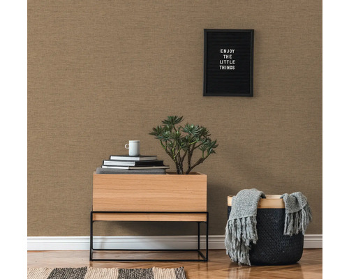 Close-up van een gestructureerd behang in een woonkamer met een klein tafeltje, een plant en decoratieve elementen