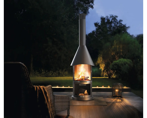 Metalen buitenhaard met hout op terras in tuin