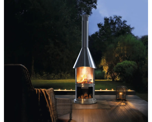 Roestvrijstalen terrasverwarmer met hout op een houten terras met tuin op de achtergrond