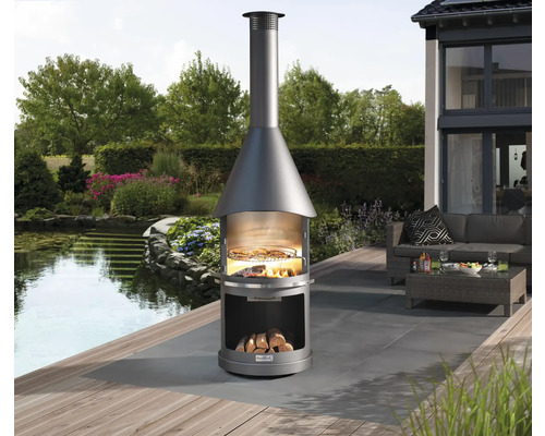 Buitenscène met een ronde houtskoolbarbecue op een terras met zitgelegenheid op de achtergrond