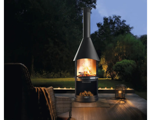 Tuinscène met tuinhaard, brandhout en kaarsen voor een gezellige buitenambiance