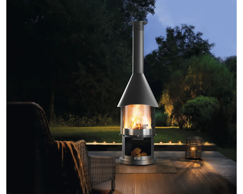 Vrijstaande buitenhaard op een terras met zithoek en kaarsen.