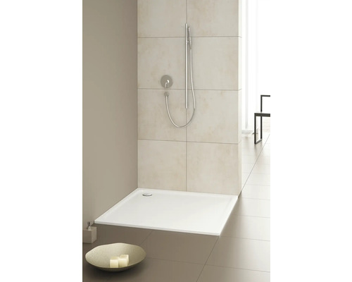 Gelijkvloerse douche met douchekop en kraan in een lichte badkamer.