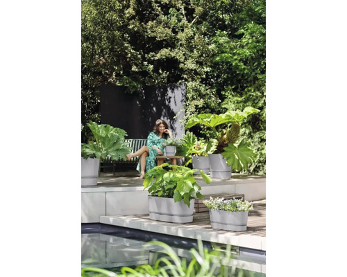 Tuin met beplanting in plantenbakken en vrouw op een bank