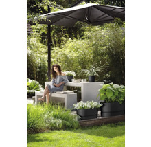 Tuinscene met vrouw, tuintafel, parasol en beplante plantenbakken