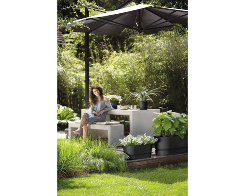 Tuinscene met vrouw, tuintafel, parasol en beplante plantenbakken