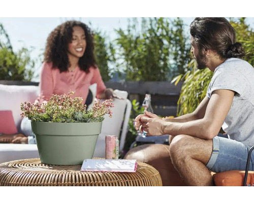 Bloempot met plant op rotan tafel met twee personen op de achtergrond