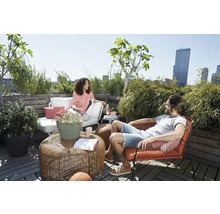 Een zonnige daktuin met zitplaatsen, planten en twee mensen.