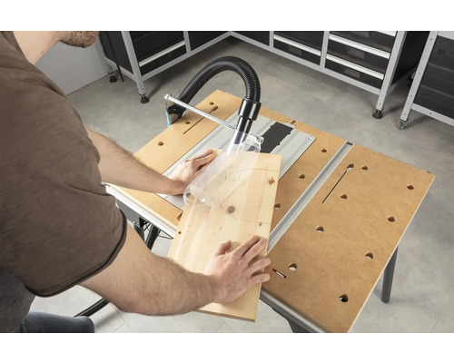 Iemand zaagt een stuk hout met een tafelzaag in een werkplaats.