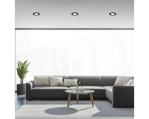 Woonkamer met grijze bank, tapijt en drie inbouwspots aan het plafond