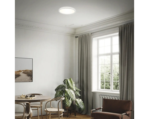 Woonkamer met ronde plafondlamp, tafel, stoelen en raam