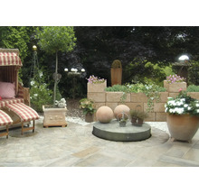 Aangelegde tuin met strandstoel, muur en plantenbakken.