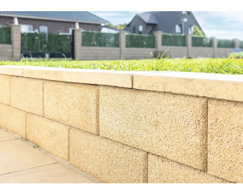 Close-up van een tuinmuur gemaakt van betonstenen met afdekking.