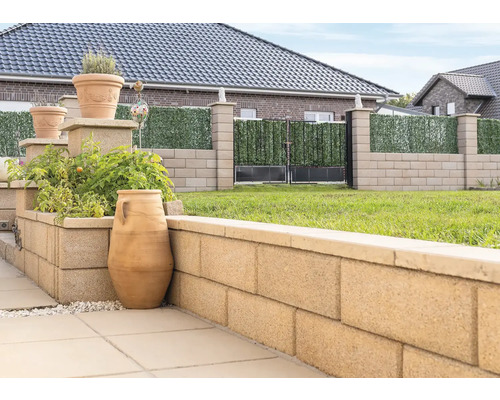 Tuinzicht met plantenbakken, muur van betonblokken en schutting met privacy scherm