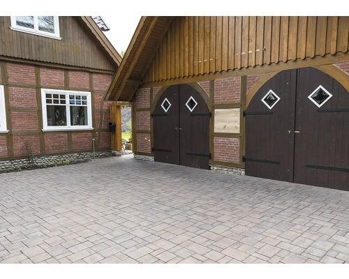 Oprit met straatstenen voor een huis met houten poort en houten elementen