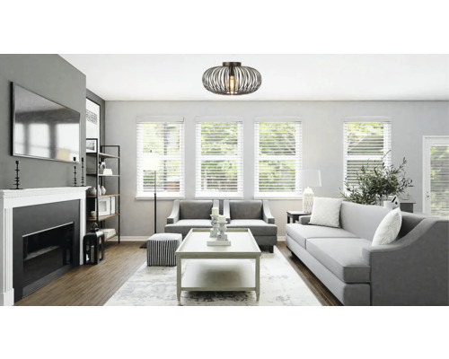 Lichte woonkamer met bank, fauteuils, open haard en decoratieve plafondlamp.