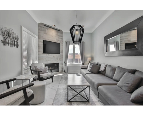 Woonkamer met bank, fauteuil, televisie en open haard.