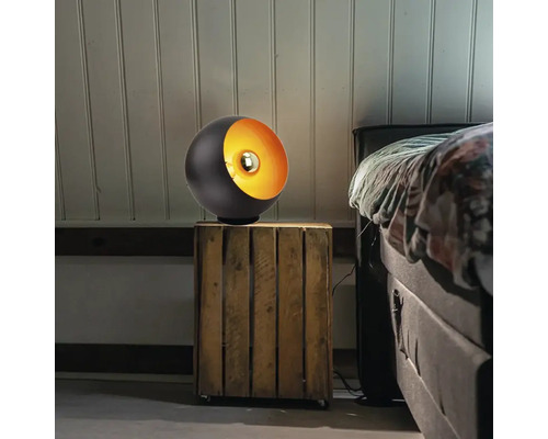 Zwarte bolvormige lamp met metalen interieur op een nachtkastje