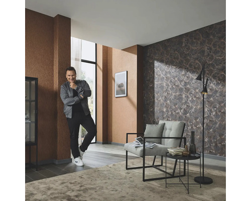 Woonkamer met gedessineerd behang, fauteuil, staande lamp en vloerkleed