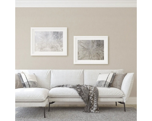 Woonkamer met bank, kussens en ingelijste afbeeldingen aan de muur