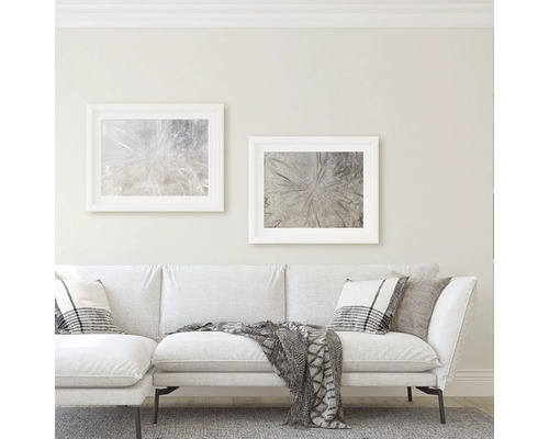 Woonkamer met bank, kussens, deken en twee ingelijste kunstdrukken