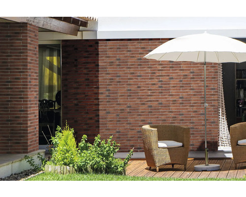 Terras met bakstenen muur, parasol en rotan stoelen.