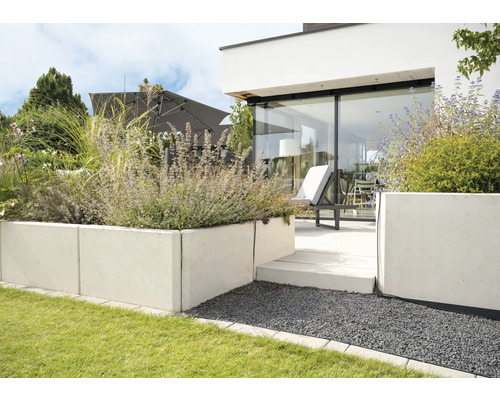 Moderne tuin met gazon, betonnen plantenbak, terras en parasol