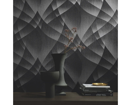 Interieurfoto van een kamer met een patroonbehang, boeken en vazen op een tafel.