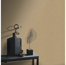 Decoratieve scène met een gestructureerd behang, aangevuld met een zwarte vaas, een gouden bol en een waaiervormig metalen sculptuur op een tafel.