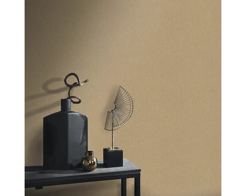 Decoratieve scène met een gestructureerd behang, aangevuld met een zwarte vaas, een gouden bol en een waaiervormig metalen sculptuur op een tafel.