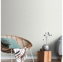 Lichte woonkamer met rotan stoel, houten tafel en subtiel patroonbehang.