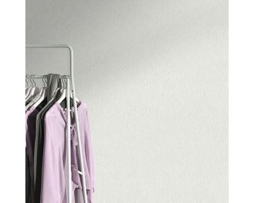 Lichtkleurig behang met textielpatroon naast een kledingrek