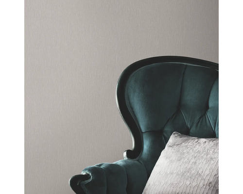 Close-up van een structuurbehang met een fauteuil op de achtergrond.