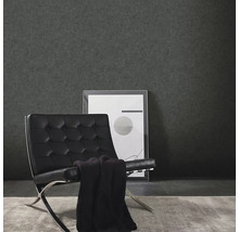 Woonkamer met donker vinylbehang, fauteuil en ingelijste foto