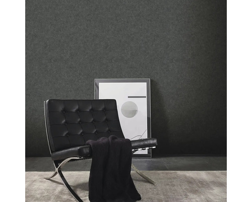 Woonkamer met donker vinylbehang, fauteuil en ingelijste foto