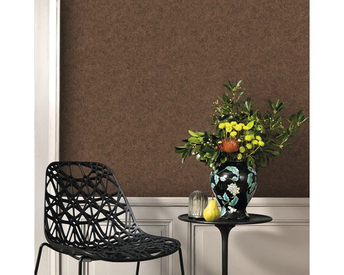 Woonkamer met bruin behang, stoel en bloemstuk op een tafel