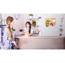 Een klant betaalt met een creditcard bij de kassa, op de achtergrond een kurk prikbord