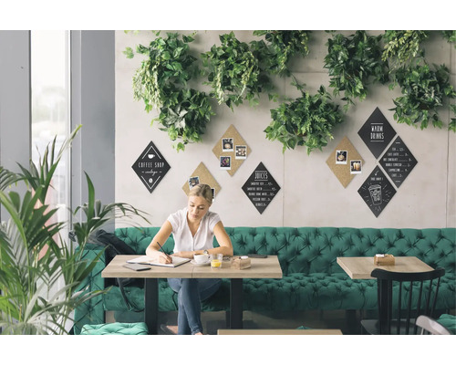 Scène van een helder café met groene decoratie, waar een vrouw aan een tafel zit te schrijven