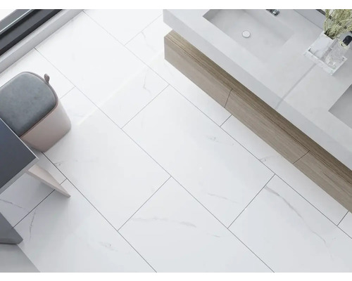 Lichte badkamer met rechthoekige vloertegels, wastafel en kruk.