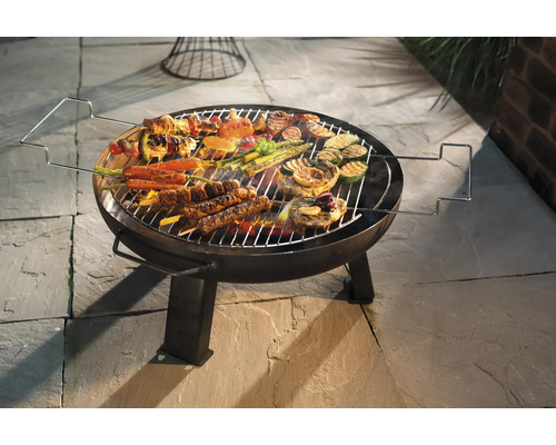 Ronde barbecue met gegrilde gerechten zoals vlees, groenten en spiesen op een stenen vloer
