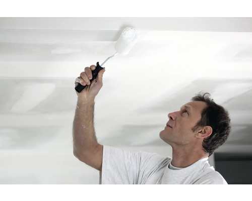 Man schildert plafond met verfroller