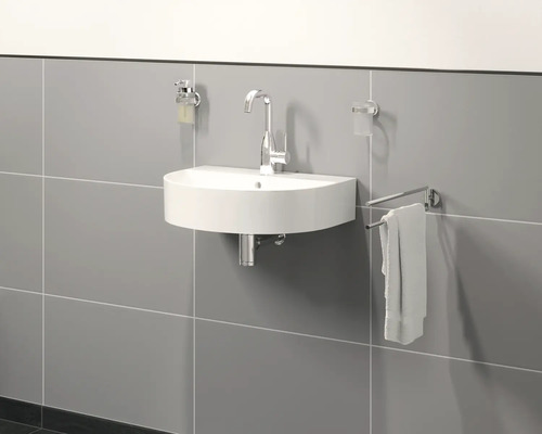 Halfronde wastafel met kraan, zeepdispenser, tandenborstelbeker en handdoekhouder aan een grijze wand