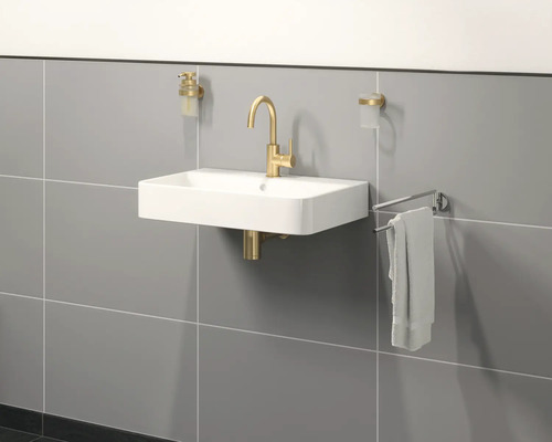 Hangende wastafel met kraan, zeepdispenser, tandenborstelbeker en handdoekhouder aan een betegelde wand