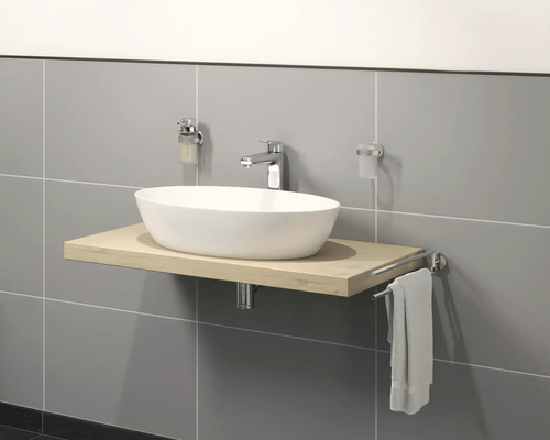 Wastafel op houten blad met kraan, zeepdispenser, tandenborstelbeker en handdoekhouder voor een grijze muur