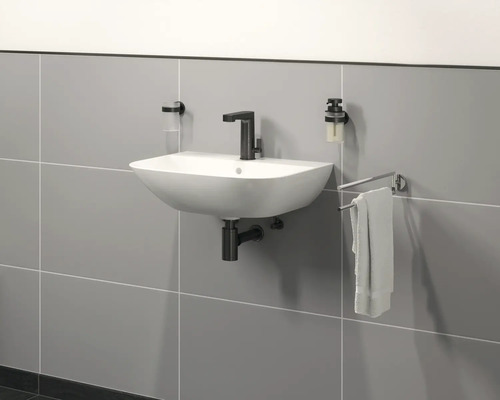 Wastafel aan de muur met kraan, zeepdispenser, tandenborstelbeker en handdoekhouder in de badkamer.