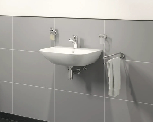 Keramische wastafel met kraan, zeepdispenser, tandenborstelbeker en handdoekhouder aan een grijze muur