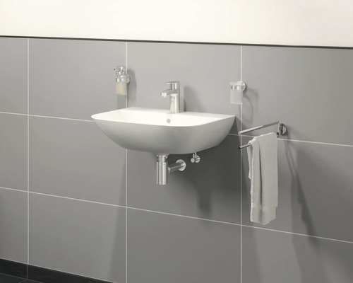 Wastafel aan de wand met kraan, zeepdispenser, tandenborstelbeker en handdoekhouder aan grijze wand