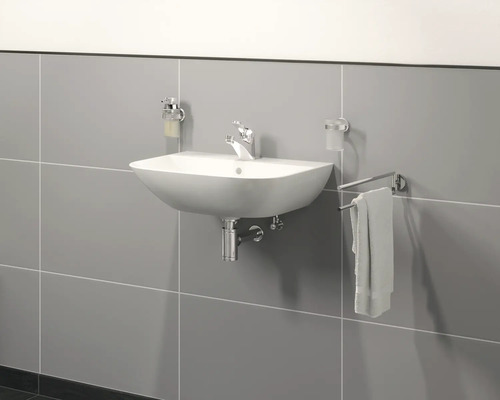 Wastafel met kraan, zeepdispenser en handdoekhouder aan een betegelde muur