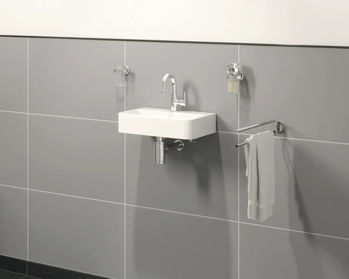 Hangende wastafel met kraan, zeepdispenser, handdoek en tandenborstelbeker in de badkamer